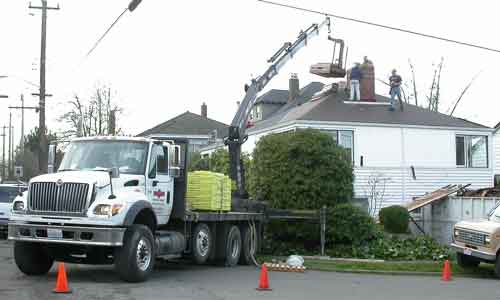 The boomtruck dropping shingles on the house