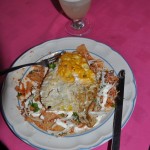 Chilaquilles with a fried egg on top. Layers of tortilla chips, chicken, tomato sauce, cheese, and cream, with lots of onions..