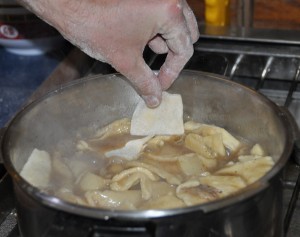 Dropping the handmade noodles into turkey broth. For a pot, we used a pressure cooker without the lid.