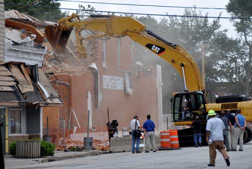 Construction equipment and workers tearing down a building