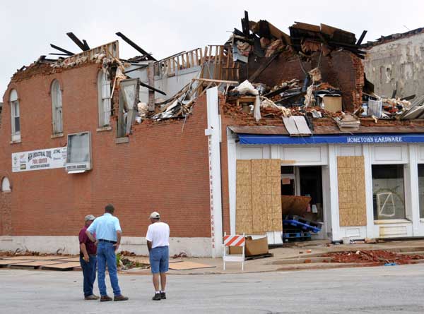 Men standing in the street beside Hometown Hardware, which was destroyed by tornado