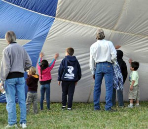 The kids watch a balloon being inflated