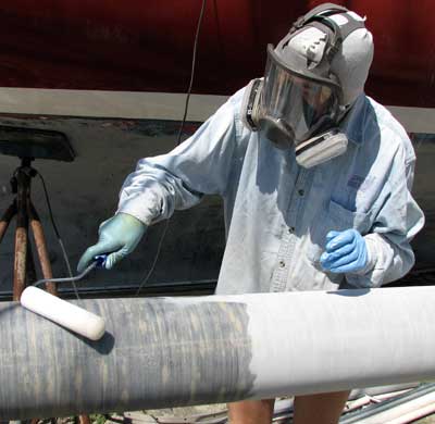 Painting a mast with epoxy Meps applying epoxy with a roller to a mast