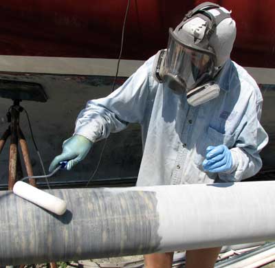 Meps applying epoxy with a roller to a mast