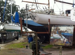 Painting of a boatyard in front of the boats